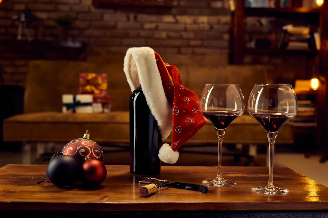 Bottle of red wine with 2 full glasses and a christmas theme